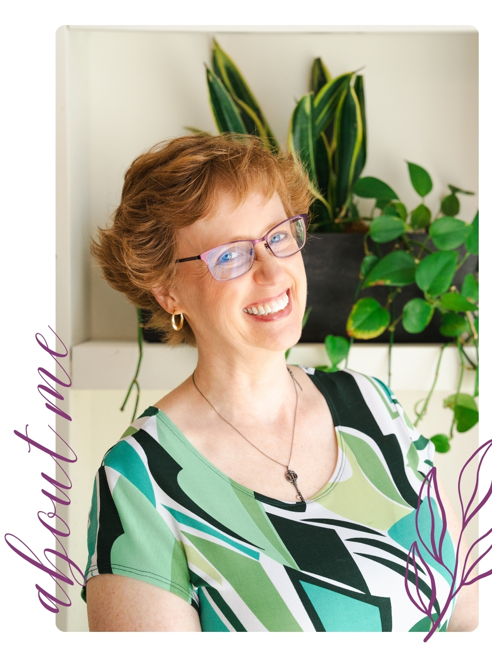 A white woman with short reddish hair smiling at the camera, wearing glasses and a green patterned top, standing in front of a shelf with green houseplants.